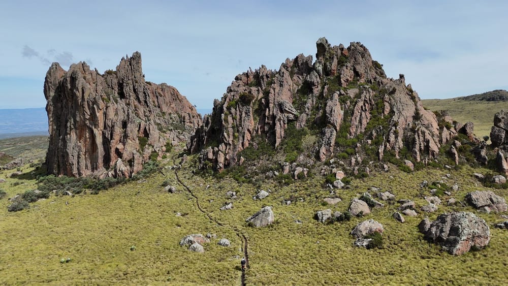 A hiker follows a moorland path towards the jagged towers of Dragon’s Teeth.