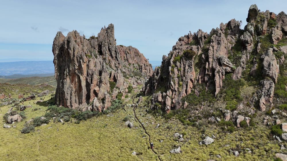A lone hiker on a thin path below the pinnacles of Dragon's Teeth